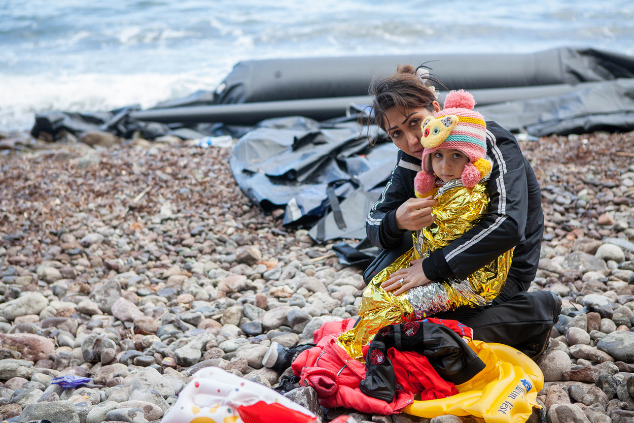 Mother warms up her child after getting off the boat. Photo by Ben White/CAFOD